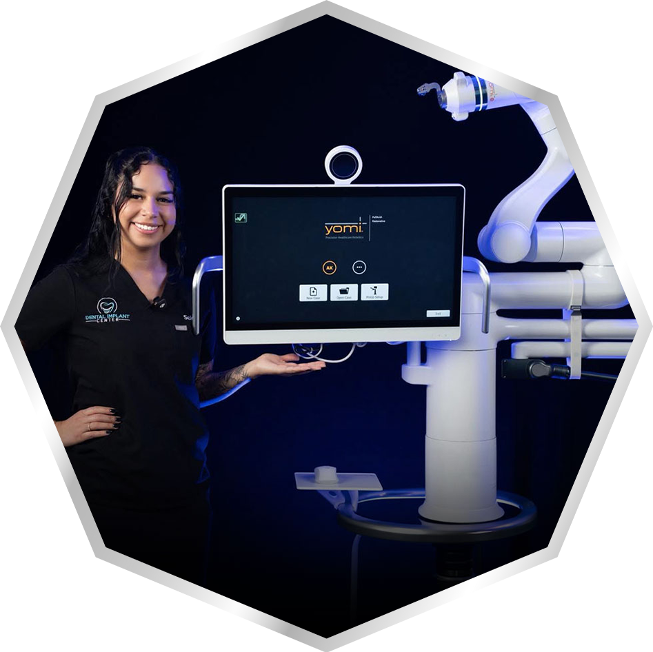 Dental team member standing beside the Yomi robotic system with its touchscreen and robotic arm.